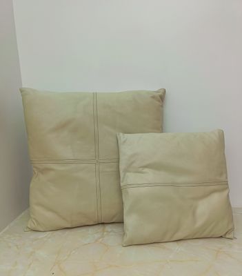beige pillows on a bed in a room with a white wall