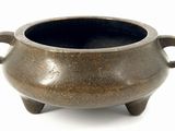 a small brown pot with handles on a white surface