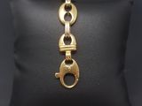 a gold plated bracelet with a clasp on a black pillow