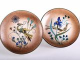 pair of decorative plates with birds and flowers on them on a white surface