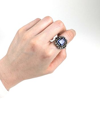 une personne tenant une bague sertie d'une pierre bleue