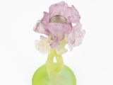 a small purple flower in a green vase on a white surface