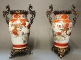 pair of vases with handles on stands on a gray surface