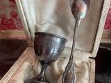 a silver cup and spoon in a case on a table
