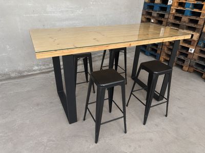 two stools and a table in a warehouse with pallets in the background