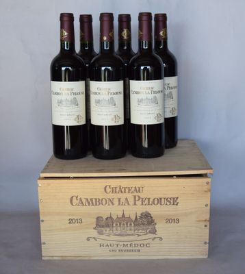 quatre bouteilles de vin rouge dans un coffret en bois posé sur une table