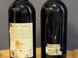 two bottles of wine sitting on a table next to each other