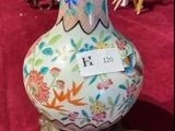 un vase posé sur une table, sur laquelle se trouve une étiquette avec un nom