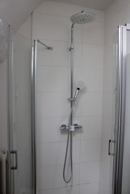 a shower in the corner of a bathroom with a glass door