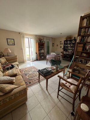 un salon avec un canapé, un fauteuil, une table et une bibliothèque
