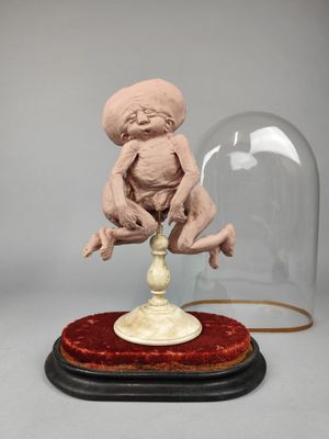 une sculpture représentant un bébé assis au sommet d'un dôme en verre
