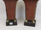 une paire de vases en bronze reposant sur des socles noirs, sur fond blanc