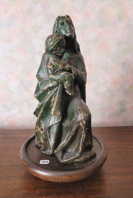 statue d'une femme tenant un bébé posé sur un plateau posé sur une table en bois