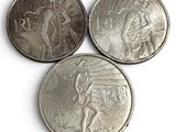 three coins with a man and a woman on them on a white surface