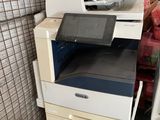 une pile d'imprimantes et de scanners dans une pièce