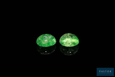 a pair of green emeralds on a black surface