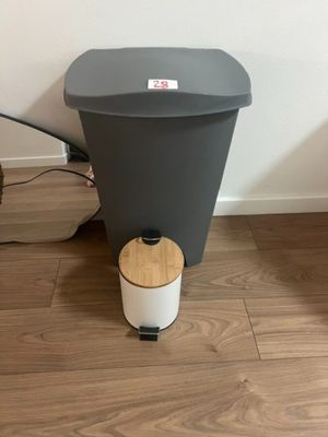 a black and white trash can next to a brown and white trash can