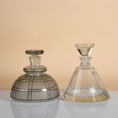 two glass vases sitting on a table with a beige background