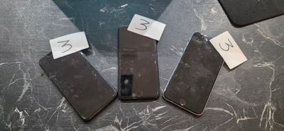 Trois téléphones portables sont posés sur une table, avec un mot accroché à chacun d'eux.