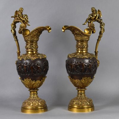 pair of antique bronze and glass vases on pedestals on a gray background