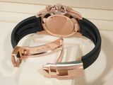 a rose gold watch with a black rubber band on a white cloth