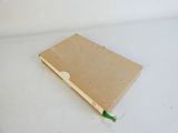 un cahier marron sur lequel est posé un stylo vert