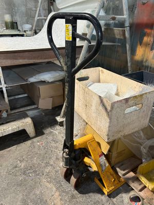 a fork truck with a box on it in front of a pile of boxes