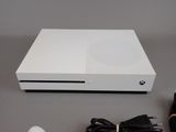 a white xbox one sitting on a table next to a charger