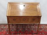 un petit bureau en bois avec des tiroirs, posé sur un tapis