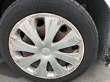 a dirty tire on a white car that is parked in a lot