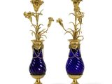 une paire de vases bleus et dorés contenant des fleurs, sur fond blanc