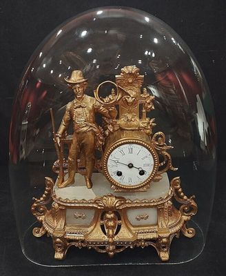 a gold clock under a glass dome on a table