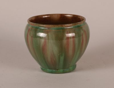 a green and red vase sitting on a white surface