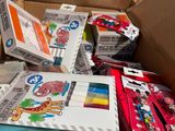 une boîte en carton remplie d'objets divers et la main d'un enfant tenant une paire de ciseaux