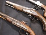 three old guns are displayed on a black surface