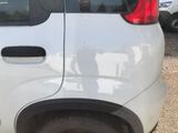 a small white car parked in a lot with a man in the back