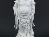 une statue blanche représentant un Bouddha souriant sur fond noir