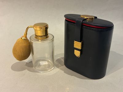 une image représentant un flacon de parfum à côté d'un étui noir