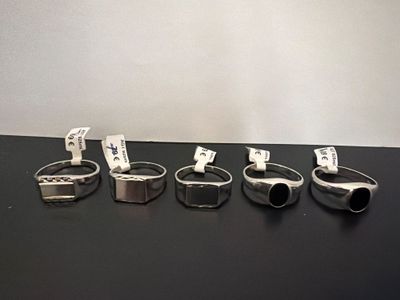 several different types of silver rings on a black surface