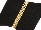 un bracelet en chaîne d'or posé sur un coussin en velours noir