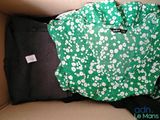 une chemise verte et blanche et un pantalon noir dans une boîte