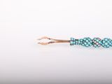 a close up of a blue beaded bracelet on a white surface