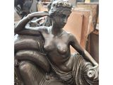 bronze statue of a woman sitting on a couch with a dog