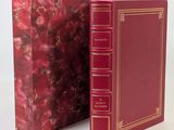 an old red book with gold trim and a red cover