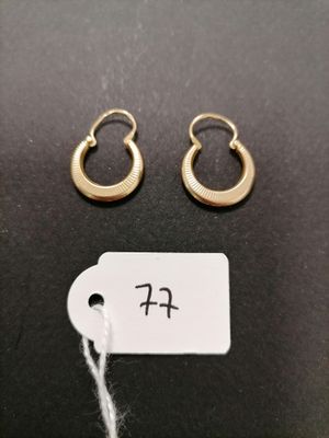 a pair of gold hoop earrings and a tag on a black surface