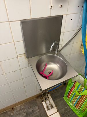 un lavabo dans un coin de la salle de bains, avec un tuyau bleu