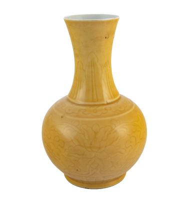 un vase jaune posé sur une surface blanche