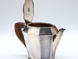 an antique silver teapot with wooden handle on a white background