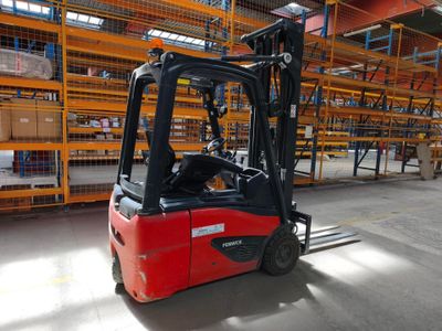 un chariot élévateur rouge dans un entrepôt rempli de rayonnages