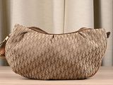 beige and brown handbag sitting on a wooden table in front of a curtain